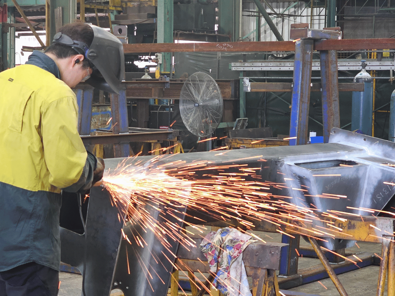 Boilermaker welding a part for a steel grizzly in a fabrication workshop