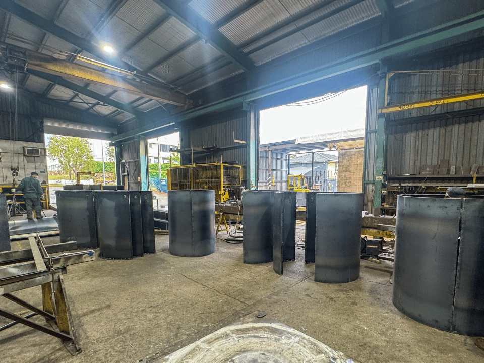 Large steel cylinders and fabricated formwork sections in engineering workshop