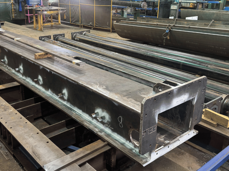 Mining liner handler fabrication showing a structural steel outer beam assembly with hydraulic cylinders in DWW Engineering’s workshop.